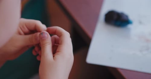 A Little Boy Plays with Bright Clay or Plasticine, Sitting at the Table.