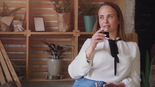 Woman Relaxing and Drinking Beverage in Cafe