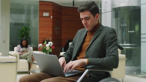 Man in Wheelchair Working on Laptop in Office
