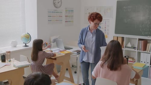 Teacher Giving Students Papers in Classroom