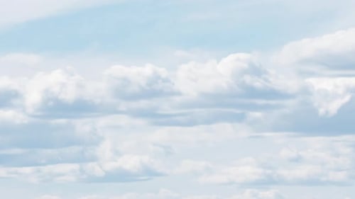 Puffy White Clouds Drifting Across Light Blue Sky