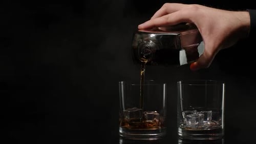 Pouring Whiskey into Glasses with Ice on Black