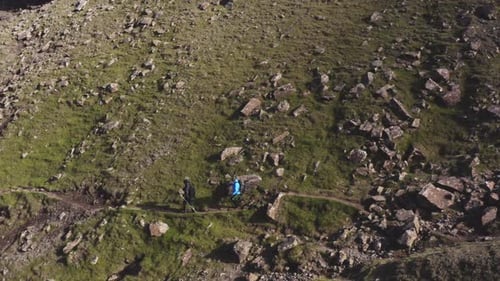 Grassy Cliff and Hills and Two Hikers Along the Trail