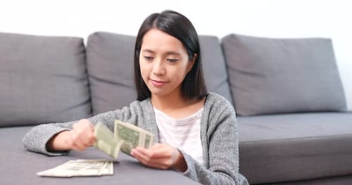 Young Woman Counting Dollar Bills at Home