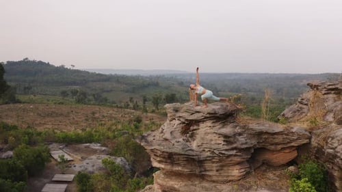 Drone Shot of a Woman By the Large Rock in the Mountains Doing Yoga Exercises
