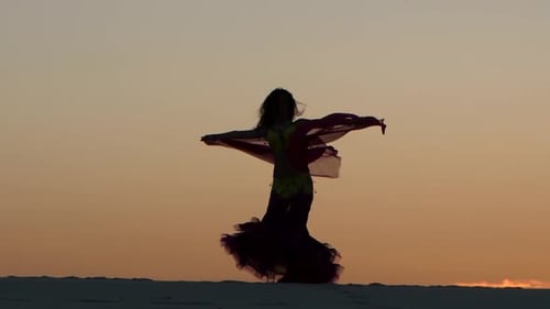 Woman Silhouetted Dancing with Fabric at Sunset