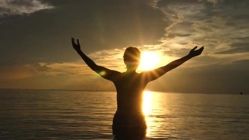 Motivational Uplifting Concept. Woman With Arms Raised At Sunset On The Beach In The Sea.