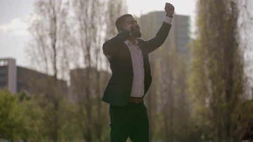 Man Celebrates Good News on Mobile Phone Outdoors