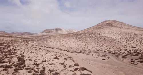 Path road in the middle of a mountains sand desert with blue bright sky in background. Arid climate