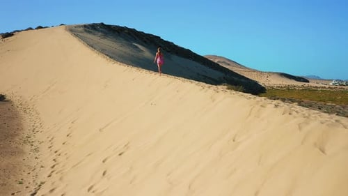 Aerial Rear View Adorable Girl Walking Among the Dunes in the Desert at Natural Park Near to Costa