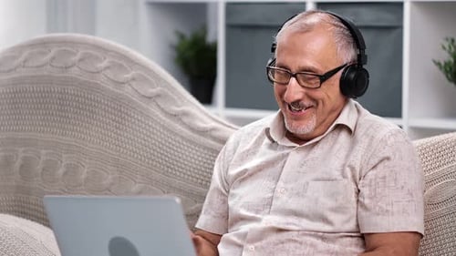 Senior Man on Laptop Video Call with Headphones