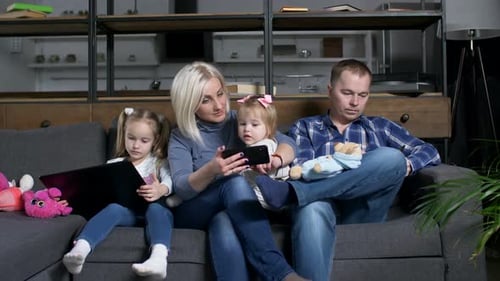 Family Relaxing with Devices on Couch at Home