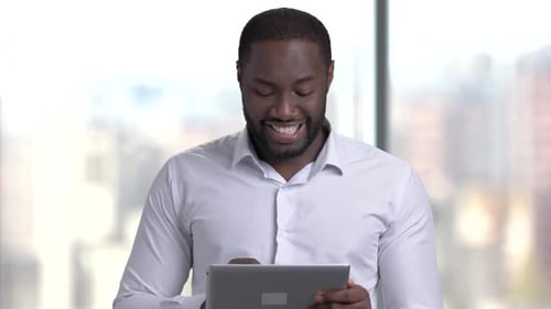 Man Smiles While Using Tablet in Office Setting
