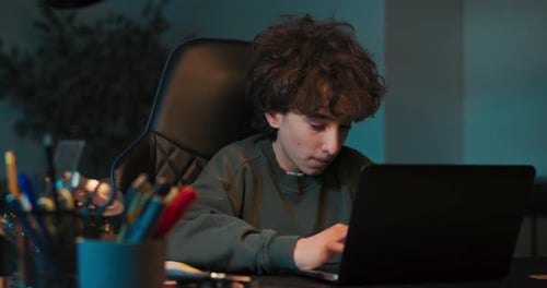 Teen Using Laptop in Dark Room at Night