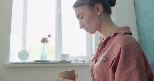 Woman Sculpting Clay Pot in Bright Studio