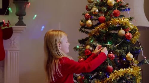 Child Decorates Christmas Tree with Ornaments and Lights
