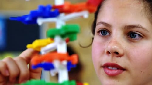 Schoolgirl experimenting molecule model in laboratory at school