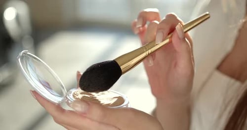 Beautiful Girl Doing Makeup with a Brush in Studio