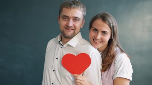 Happy Couple Holding Red Paper Heart Smiling