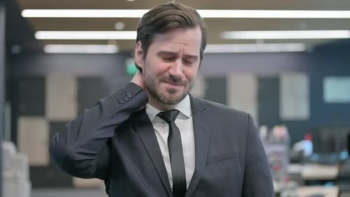 Man in Suit Rubs Sore Neck in Office