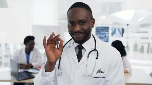 Afrikanischer Arzt blickt mit Team von Cowoker in die Kamera