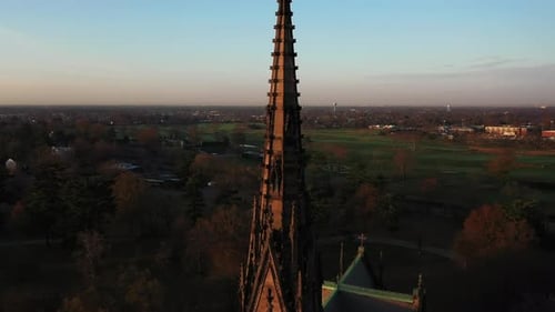 An aerial shot of a cathedral's tall steeple, taken at sunrise. The camera dolly out from the church