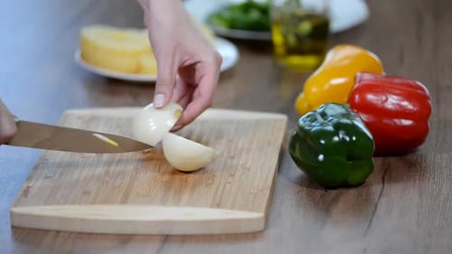 Hands Cutting Onion on Board with Knife
