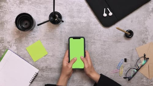 Smartphone with green screen on work table, view from above
