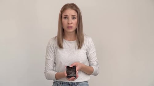 Woman Looks Sadly at Cracked Mobile Phone Screen