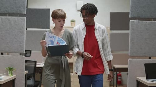 Two Multiethnic Colleagues Going along Office and Chatting