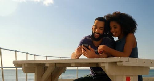 Couple using mobile phone in the beach 4k