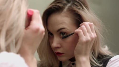 Woman Applying Mascara in Front of a Mirror
