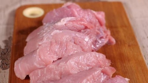 Pork Is on the Board. Sliced Pork Meat. Cook's Hands Were Clad in Latex Gloves.