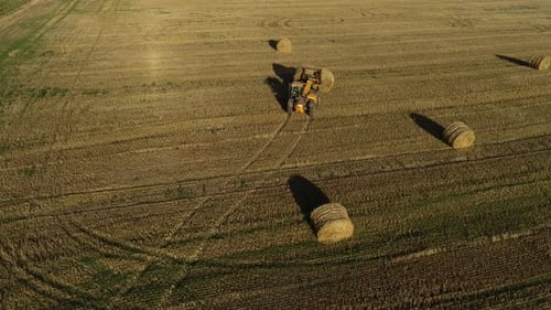 Tractor Moving Hay Bales in Rural Field Aerial