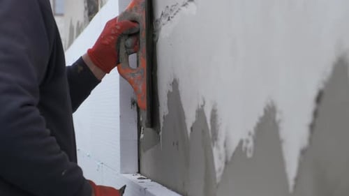 Worker applies stucco to building exterior