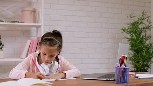 Girl Writes in Notebook Doing Homework at Desk