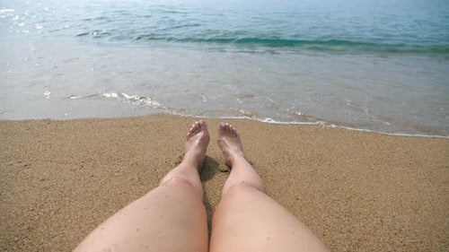 Point of View of Young Woman Lying on Yellow Sand at the Beach By the Sea and Tanning