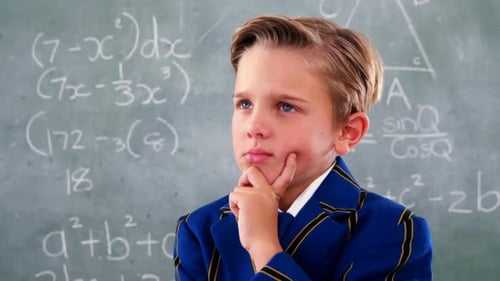 Boy Thinks in Front of Chalkboard with Math