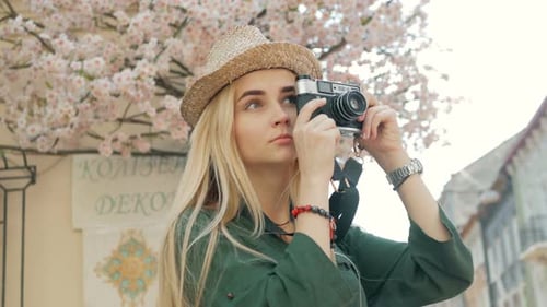 Young woman tourist taking a picture on retro camera of a city on vacation