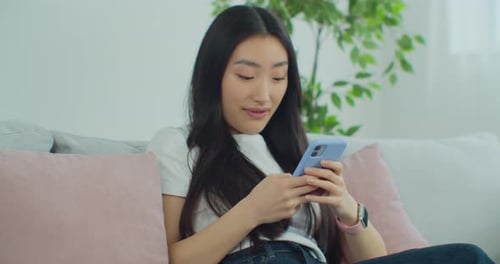 Woman Using Mobile Phone on Couch at Home