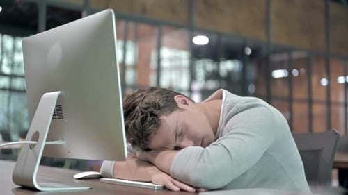 Tired Young Guy Having Quick Nap at Office Desk