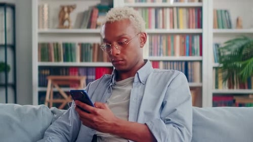 Young Adult Using Smartphone at Home on Couch