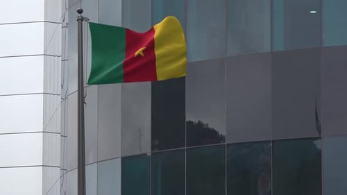 Cameroon Flag Waving on Flagpole In Front Of Modern Building