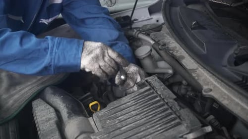 La
main en gros plan de la femme est un mécanicien réparant le moteur de la voiture dans le garage, service automobile.