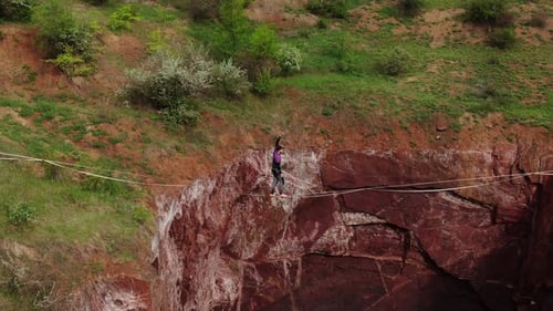 Young Man Is Slacklining Over a Deep Pit Walking on Tightrope High Angle View