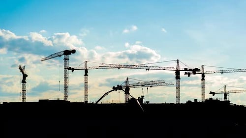 Construction Cranes Silhouetted Against Blue Sky
