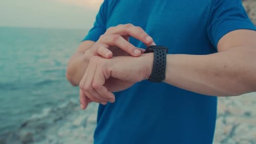 Man Views Smartwatch at the Beach