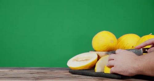 Des hommes coupent un melon en morceaux sur une planche à découper.