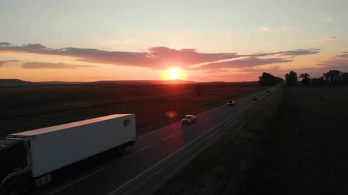 Aerial shot: flying along road with driving vehicles, trucks and cars.