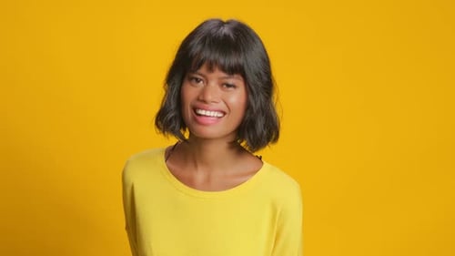 Smiling Woman in Yellow Against Bright Background